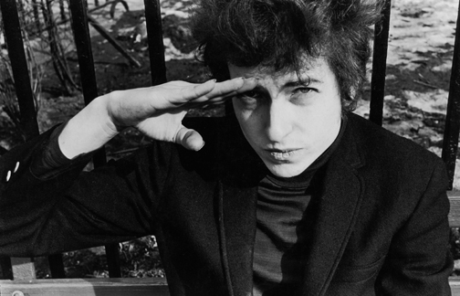 American musician Bob Dylan (born Robert Zimmerman) salutes as he sits on a bench in Sheridan Square Park, New York, New York, January 22, 1965. (Photo by Fred W. McDarrah/Getty Images)